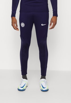 Pantaloni atletici blu navy con logo bianco Nike ed emblema del club. Presentano un motivo testurizzato sui lati e una vestibilità affusolata. Adatti per attività sportive.