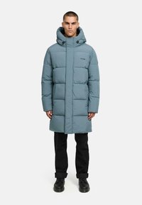 Light blue padded coat featuring a high collar, hood, and zip closure, with a quilted pattern and black logo detail on the chest.