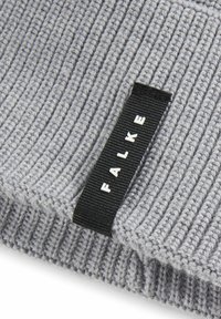 Maglione grigio a coste con tessuto testurizzato. Presenta un'etichetta nera con scritte bianche "FALKE." Mettere a fuoco il motivo e il design del tessuto.