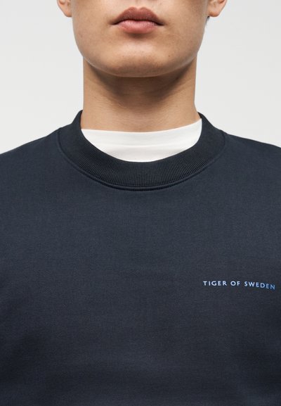 Μπλε σκούρο φούτερ από βαμβάκι, με ριμπ λαιμόκοψη και μικρό μπλε λογότυπο "TIGER OF SWEDEN" στο στήθος.