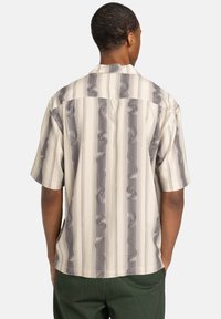 Short-sleeve shirt in light fabric, featuring a wavy gray and cream striped pattern, with a relaxed fit and open collar design.