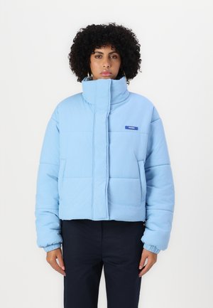 Lyseblå cropped pufferjakke med høy krage, quiltet mønster, sidelommer og "HUGO"-logo på brystet. Elastiske mansjetter er tilstede.