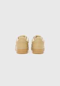 Yellow low-top sneakers with a smooth leather upper, white accents, and a translucent rubber sole. Features TOMMY JEANS branding on the heel.