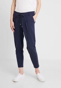 Marina joggerbyxor i mjukt tyg med elastisk midja och dragsko. Utrustad med sidofickor och tapered bendesign. Bärs med vita sneakers.