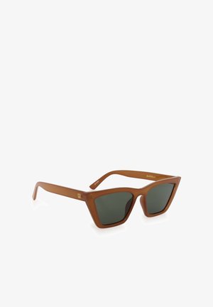 Lunettes de soleil cat-eye marron avec des verres foncés et un petit logo doré sur les branches, présentées sur fond blanc.