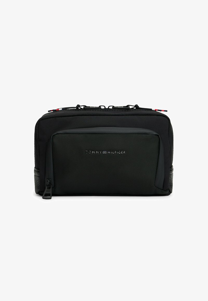 Black rectangular toiletry bag with front zip pocket and dual top zippers, featuring small Tommy Hilfiger logo on front pocket.