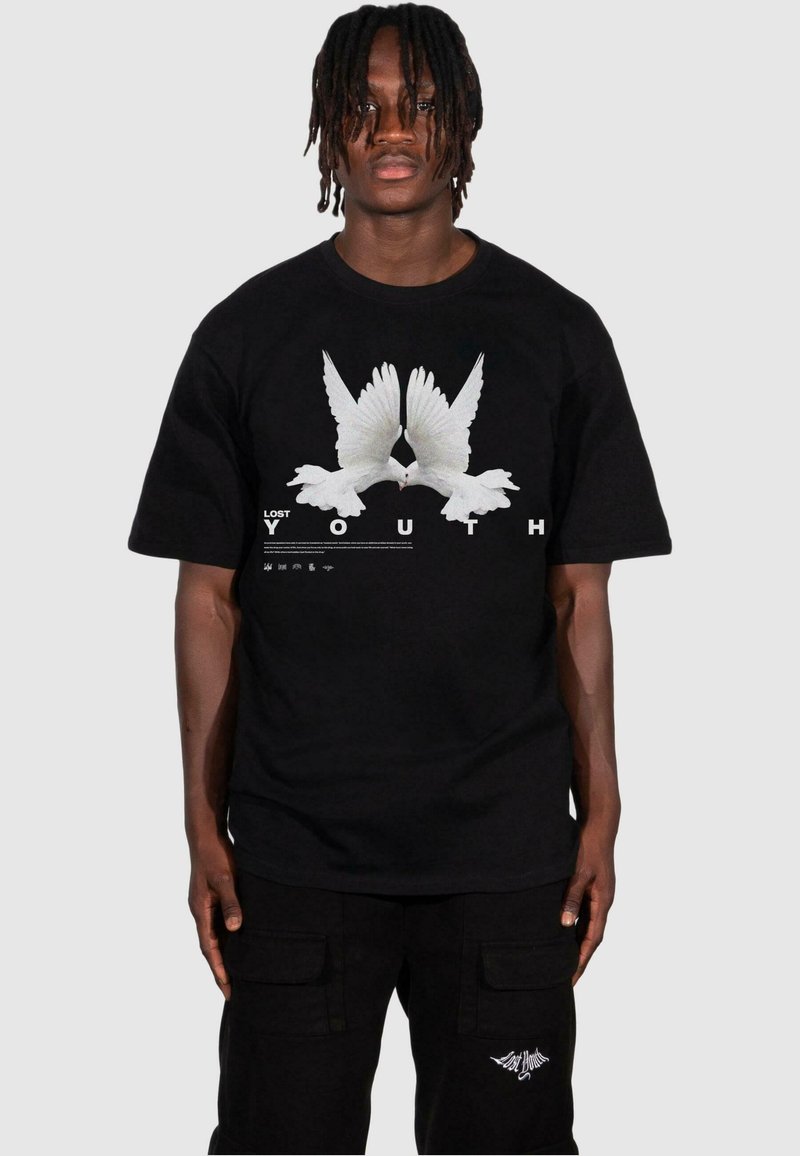 T-shirt en coton noir avec un graphique de deux colombes blanches et le texte "JEUNESSE PERDUE" en lettres audacieuses en dessous, à manches courtes et à coupe décontractée.