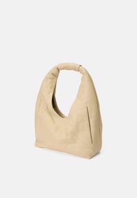 Sac à main en cuir beige avec une silhouette courbée, texture douce et deux zippers latéraux. Doté d'une poignée enroulée pour un transport facile.