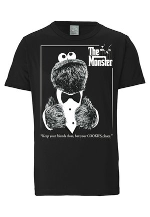 Czarny T-shirt z Cookie Monster w smokingu, z napisem "The Monster" oraz cytatem "Trzymaj przyjaciół blisko, ale ciasteczka jeszcze bliżej."