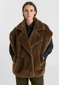 Bruine mantel van namaakbont met een omslagkraag, dubbele knoopsluiting aan de voorkant en zijzakken, met een zachte textuur en een oversized silhouet.