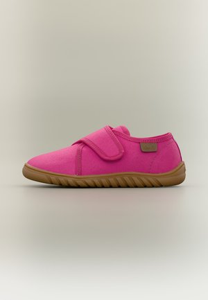 Chaussure décontractée rose vif avec une large bride Velcro et une semelle en caoutchouc marron texturée sur un fond neutre.