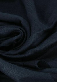 Tessuto testurizzato blu navy, arrotolato, con un aspetto morbido e liscio e un foro visibile su un lato, che indica un possibile usura o un dettaglio di design.