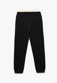 Zwarte, gestructureerde sweatpants met een crèmekleurige elastische tailleband en manchetwonden enkels, met een relaxed fit en zonder zichtbare zakken.