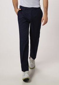 Námořnické modré kalhoty s tailoringovým střihem, vyrobené z hladké tkaniny. Spárovány se světle šedými botami s limetkovými akcenty a perforovaným designem.