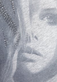 Tela de algodón gris que presenta una impresión en medio tono de una cara, con texturas punteadas y un diseño abstracto en capas en tonos monocromáticos.