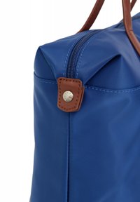 Borsa in nylon blu con dettagli in pelle marrone, dotata di zip superiore e forma arrotondata. Dettaglio in metallo notevole sul lato.