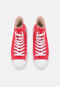 Czerwone płócienne sneakersy typu high-top z białymi sznurówkami, gumowymi podeszwami i kontrastowym białym przeszyciem. Oferują okrągły nos i wyściełany kołnierz w okolicy kostki.