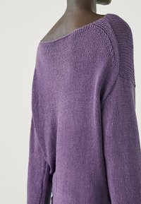 Pull en maille violet avec une coupe surdimensionnée et décontractée. Motif texturé avec un large col et des épaules tombantes, mettant en valeur un tissu doux.