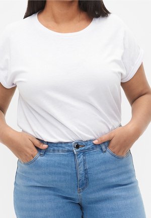 Weißes T-Shirt mit kurzem Arm und Rundhalsausschnitt, kombiniert mit hoch taillierten blauen Jeans mit Knopfverschluss und Fronttaschen.