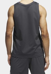 Bezramenný sportovní top tmavě šedé barvy, vyrobený z prodyšné síťoviny. Disponuje kulatým výstřihem a volným střihem, vhodný pro sportovní oblečení.