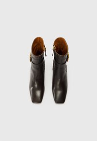 Brown leather ankle boots with a square toe, featuring a subtle buckle detail and a warm brown interior. Smooth texture, sleek design.