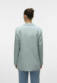 Blazer su misura azzurro chiaro realizzato in tessuto morbido, con uno spacco posteriore singolo, rever a punta e maniche lunghe. Design minimalista.