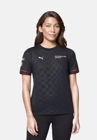 Czarna koszula krótko rękawowa w wzór w kratkę. Posiada logo Pumy na piersi oraz branding Porsche Motorsport w kolorze czerwonym. Gładka faktura.