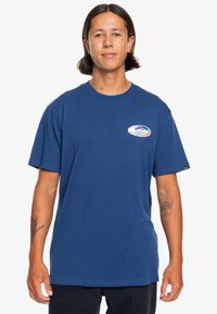 Blue cotton t-shirt with short sleeves, crew neckline, and a circular logo design in white, blue, and orange on the left chest.