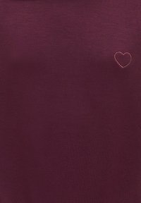 Tissu violet foncé uni avec un petit contour de cœur simple cousu en haut à droite.