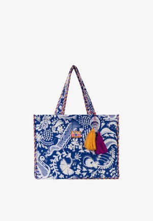 Blauwe draagtas met witte bloemen- en vogelpatteren, met twee stoffen handvatten en gele en paarse kwastjes die aan de voorkant hangen.