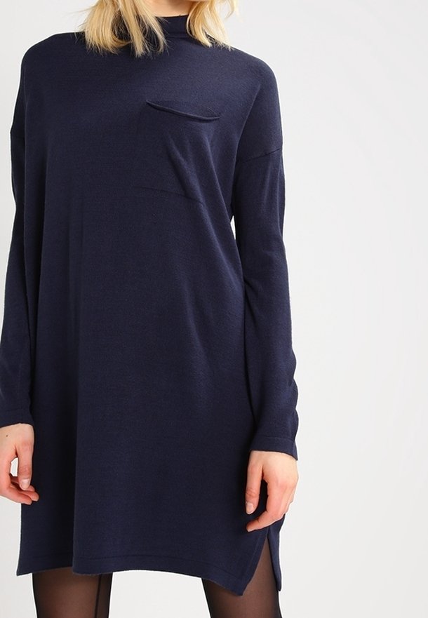 Mörkblå oversize-klänning i mjukt tyg med långa ärmar, rundad halsringning och en liten bröstficka. Kanten har sidospalter.