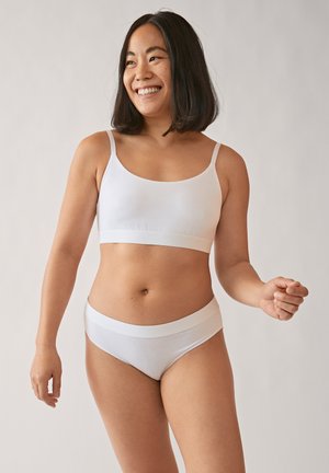 Bralette blanche sans coutures avec bretelles fines et culotte taille basse assortie. Texture lisse et bande inférieure de style bandeau. Design minimaliste.