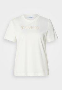 T-shirt en coton blanc avec des manches courtes et un col rond, portant le mot "TENIS" en lettres texturées en relief sur le devant.