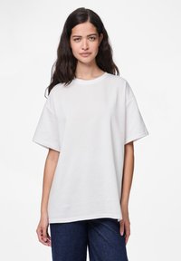 Hvit bomull T-skjorte med rund hals, korte ermer og oversized passform, med en glatt tekstur og uten synlige mønstre eller detaljer.