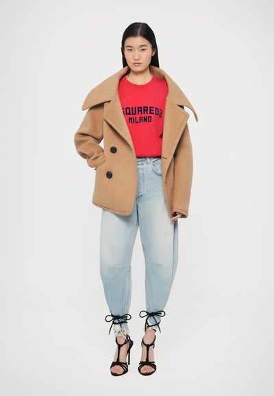 Tevebarna, dupla soros gyapjúkabát nagy gombokkal, piros grafikás pólóval és világoskék, megkötős szegélyű, szakadt farmerrel párosítva. Fekete pántos magassarkú.