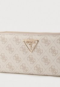 Bézs cipzáras pénztárca dombornyomott mintával. Fém háromszög alakú logóplakett jellemzi. Texturált felület és varrott részletek.