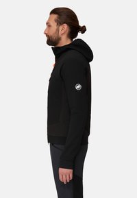 Black hooded jacket with orange accents, featuring a zip front, textured panels, and logo on the left sleeve. Slim fit design.