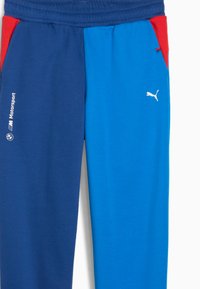 Blaue und dunkelblaue Sweatpants mit roten Akzenten, elastischem Taillenbund, seitlichen Taschen und weißem Puma-Logo am Bein, aus weichem Material gefertigt.