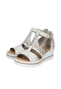 Wedge sandals in metallic silver with cut-out floral patterns. Open toe design, cushioned insole, and adjustable ankle strap. White rubber sole.