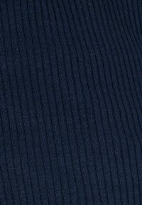 Marine ribbelstof met smalle verticale groeven. Zachte textuur met een gebreid patroon, geschikt voor verschillende kledingstukken of bekleding.