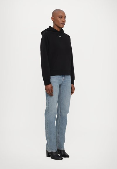 Svart hettegenser med frontlomme, ribbede mansjetter og hette. Kombinert med lyseblå rettskårne jeans og svarte hæl ankle støvler.