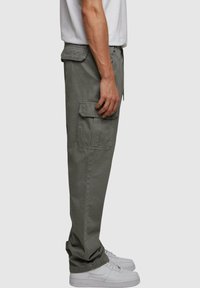 Olijfgroene heren cargo broek van katoen met zijzakken, rechte pijpen en een comfortabele pasvorm, gecombineerd met witte sneakers.