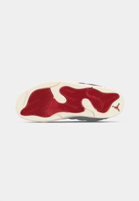 Semelle en caoutchouc rouge et blanche à motif avec un design en vagues, mettant en valeur un accent gris et un logo Jumpman. Texture douce, forme flexible.