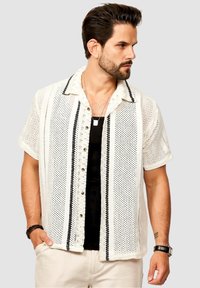 Leichte, cremefarbene Strickbutton-up-Bluse mit schwarzen Streifen, kurzen Ärmeln und entspannter Passform. Mit sichtbarem Knopfverschluss und strukturiertem Stoff.