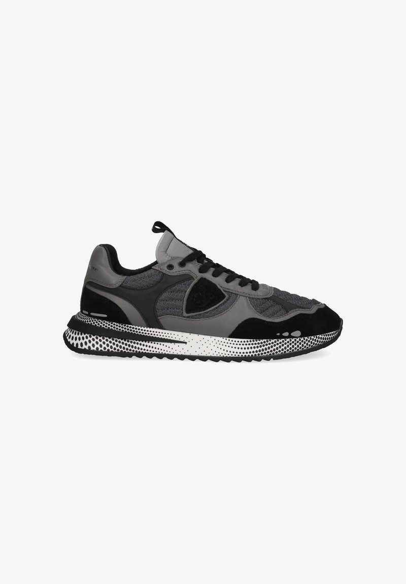 Grey and black sneaker featuring a textured upper, mesh panels, and a rubber sole with dotted accents. Laces and pull tab included.