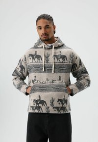 Lichtgrijze hoodie met een Western-geïnspireerde print met zwarte paarden- en cactussenmotieven. Het heeft een kangoeroezak en een capuchon met trekkoord.