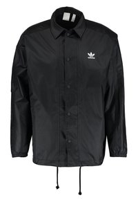 Svart nylonjacka med tryckknappslås framtill, krage, elastiska ärmslut, justerbar dragsko i fållen och vit Adidas-logotyp på bröstet.