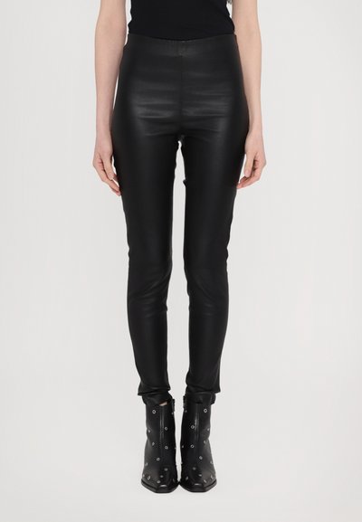 Zwarte faux leren leggings met een slim fit, hoge tailleband en een gladde textuur. Draag ze met zwarte enkellaarzen met zilveren ooggaten.