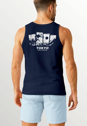 Navyblaues Tanktop mit einem weißen Grafikdruck von Bergen und einer Sonne auf dem Rücken, mit dem Text "TOKYO" darunter. Aus Baumwollmaterial, ärmelloses Design.