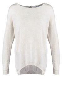 Ljusbeige oversized tröja med långa ärmar, rundad halsringning och rundad nederkant. Tillverkad av mjukt, strukturerat material med avslappnad passform.